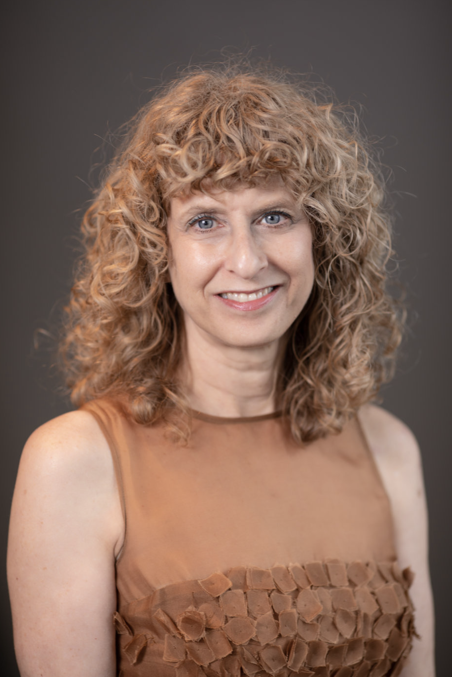 a smiling woman with curly hair looking at the camera